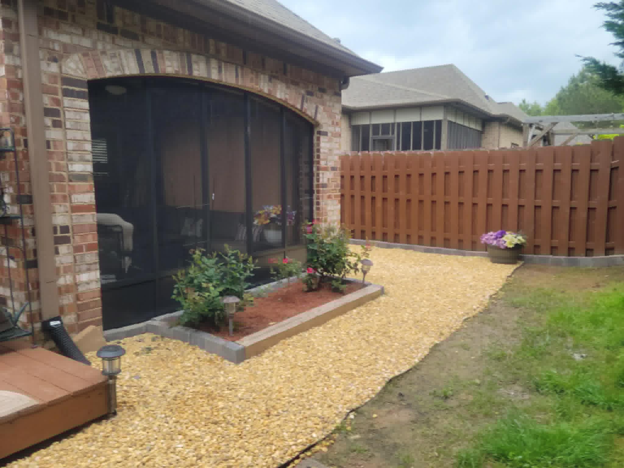 Landscaped backyard with gravel path, garden bed, and wooden privacy fence.