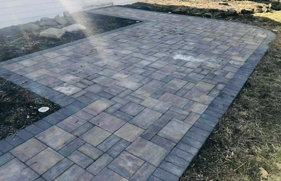 Geometric patio made of interlocking concrete pavers beside a home.